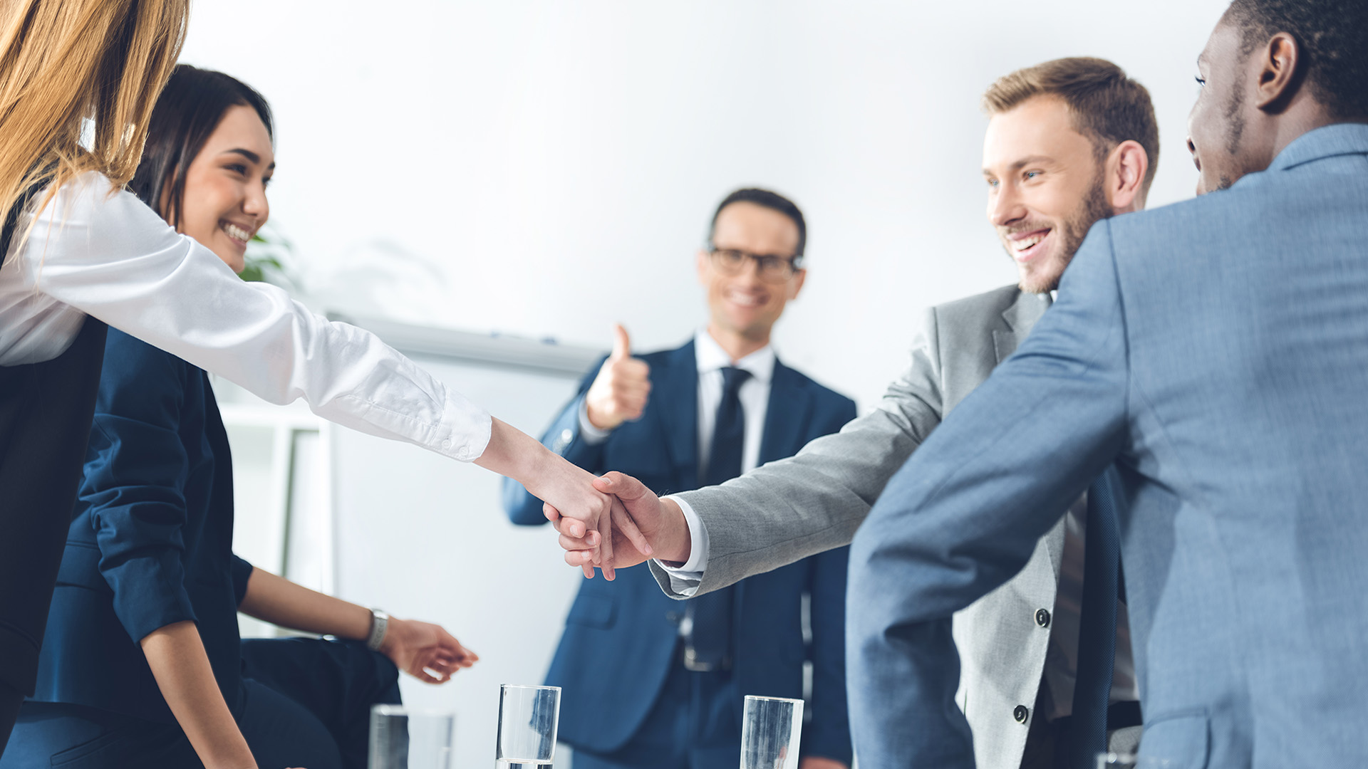 businesspeople shaking hands in conference hall while team leade